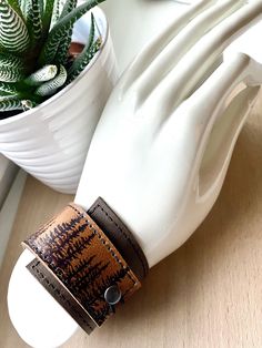 "I've made this wrapping cuff out of soft, scuffy brown and sienna brown leather. The leather has been hand printed with an image using indelible (permanent) ink. Machine stitched, it has an attached elastic that hooks over a button, so this cuff will adjust to fit most wrist sizes 5.75\" to 7\" in circumference. At the narrowest, the width of the cuff is 1.25\" and at the widest it's 2\". Only premium quality leather and supplies are used to handcraft each item. Small imperfections may exist in Brown Adjustable Cuff Bracelet, Adjustable Brown Cuff Bracelet For Everyday, Adjustable Cuff Wristband, Adjustable Brown Cuff Bracelet With Bracelet Strap, Adjustable Brown Cuff Bracelet With Strap, Adjustable Brown Cuff Jewelry, Cuff Wristband With Bracelet Strap Gift, Adjustable Cuff Wristband As Gift, Adjustable Brown Bracelet Wristlet