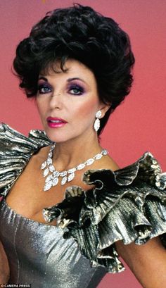 an older woman with dark hair wearing a silver dress and large earrings, posing for the camera