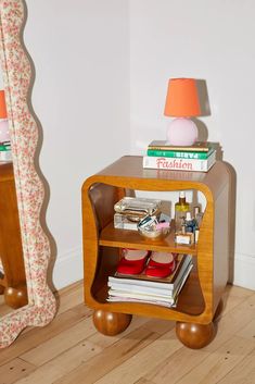 a small wooden table with books on it and a lamp in the corner next to it