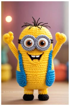 a crocheted minion with glasses on it's head and arms in the air