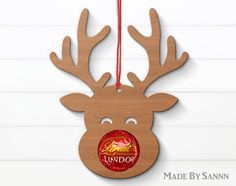 a wooden reindeer ornament hanging on a wall with a red string attached to it