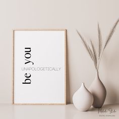 two vases sitting next to a framed poster on a wall with the words do you unapolocgeticallyly written in black