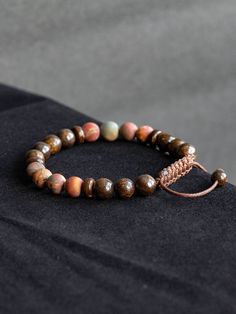 This bracelet is made with natural polished Bronzite Jasper and matte Picasso Jasper in size 8mm. Beautiful elegant yet minimalist design is perfect gift for self or your loved ones. Bracelet is 7'' long and has adjustable macrame knot that enables the cords to slide through and expand in size for comfortable fit.  Bronzite is used for protection, as it not only repels, but also sends back the negative energies to the sender. Spiritually, Bronzite assists us in achieving a state of certainty without willfulness, allowing us to easily adapt to the best path to take. It clears confusion, helping our ability to make decisions and choices about our life path. Bronzite is a "stone of courtesy", especially helpful to people who greet and assist the public. It will even instil a polite nature in Rustic Gemstone Beaded Bracelets As Gift, Rustic Beaded Bracelets With Gemstone Beads For Gifts, Rustic Beaded Bracelet With Gemstone Beads For Gifts, Jasper Beaded Bracelets With 8mm Beads As Gift, Hand-strung Jasper Beaded Bracelets As Gift, Adjustable Brown Jasper Bracelet, Adjustable Jasper Beaded Bracelets With 8mm Beads, Earthy Hand-strung Bracelets, Earthy Hand-strung Round Bead Bracelets