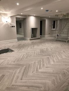 an empty room with wood flooring and stairs in the center, surrounded by white walls