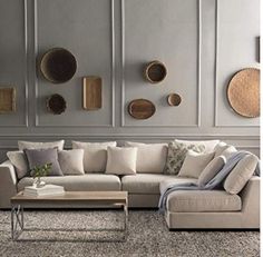 a living room filled with lots of furniture next to a white wall covered in plates