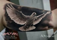 a black and white tattoo of a dove flying in the sky with its wings spread out