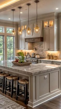 a large kitchen with lots of counter space and lights hanging from the ceiling over the island