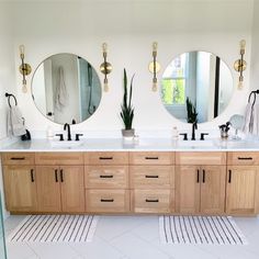 a bathroom with two sinks and three mirrors on the wall above them are plants in pots