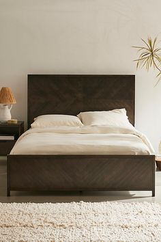 a large bed sitting on top of a white rug next to a table and lamp