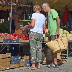 two people standing in front of a fruit stand