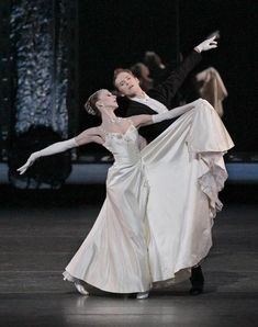 two ballerinas are dressed in white and black, one is holding the other