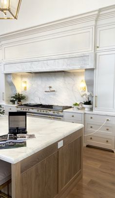 an open laptop computer sitting on top of a kitchen counter next to a stove and oven