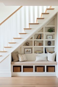 a white staircase with bookshelves and storage under the bannister in this living room