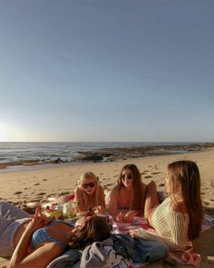 three women sitting on the beach having a picnic