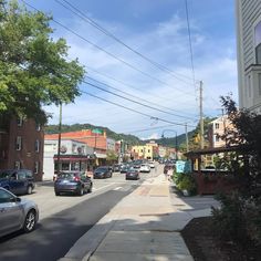 cars are driving down the street in front of buildings and telephone poles on both sides