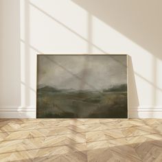 an empty room with a large painting on the wall and wooden floor in front of it