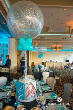 a table set up for a party with blue and white decorations, balloons and plates