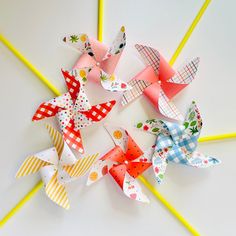 several different types of paper flowers on yellow sticks with white and blue checkered bows