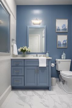 a bathroom with blue walls and white tile on the floor, along with a toilet and sink