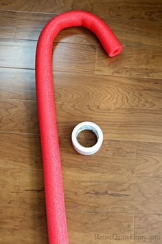 a red pipe laying on top of a wooden floor next to a roll of tape