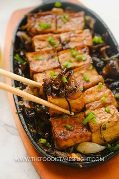 tofu and onions in a pan with chopsticks