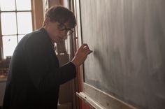 a young man writing on a chalk board