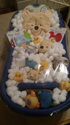 a baby bath tub filled with lots of stuffed animals and toys on top of a wooden table