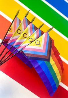 several colorful kites with arrows sticking out of them on a rainbow striped background,