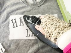 a person holding a cell phone on top of a gray and white t - shirt