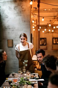 a woman standing in front of a table filled with people