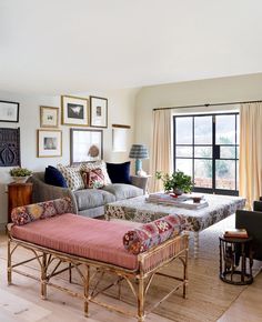 a living room filled with lots of furniture and pictures on the wall above it's windows