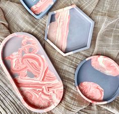 three soap trays sitting on top of a bed next to each other with pink and white designs