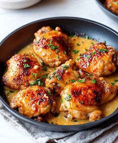 two pans filled with chicken and sauce on top of a table