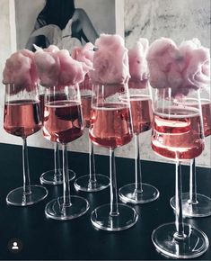 four wine glasses filled with pink cotton candy on top of a black table next to each other