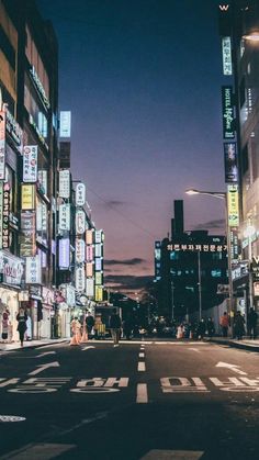 an empty city street at night with neon signs on the buildings