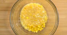 a glass bowl filled with corn on top of a wooden table