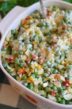 a white bowl filled with peas and other food on top of a checkered table cloth