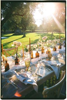 an outdoor table set up with white flowers and place settings for dinner in the sun