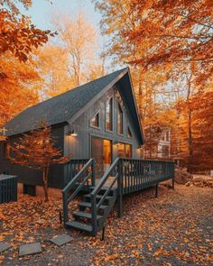 a cabin in the woods surrounded by fall leaves