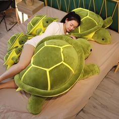 a woman laying on top of a green turtle pillow