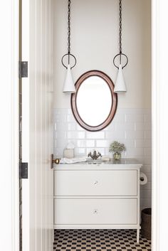 a bathroom with black and white checkered flooring, round mirror above the sink