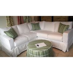 a white sectional couch with green and white pillows