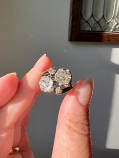 a woman's hand holding an old diamond ring in front of her face,