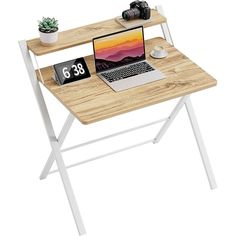 a laptop computer sitting on top of a wooden desk next to a plant and camera