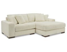 a white sectional couch with pillows on it's back and the seat facing outward