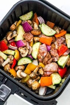 a pan filled with chicken and vegetables on top of a stovetop oven burner