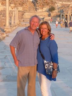 a man and woman standing next to each other in front of an ancient building with columns