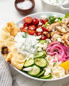 a salad with chicken, cucumbers, tomatoes, onions and pita bread