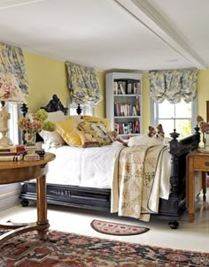 a bed sitting in a bedroom next to a table with a lamp on top of it