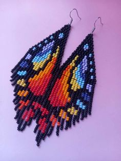 a pair of black and red beaded earrings with multicolored designs on them